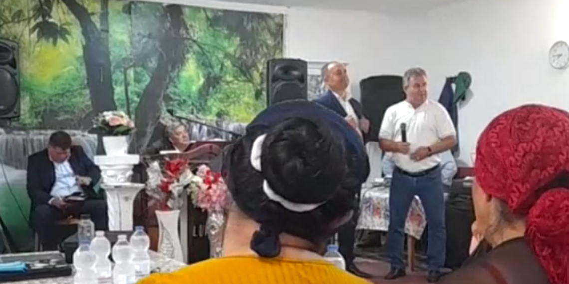 VIDEO. Înregistrări halucinante cu primarul de Ineu în campanie la biserica din colonia de rromi. Spune că Morna, contracandidatul său va trimite milițienii să-i băge în lagăre. „Eu trec pe lângă voi, nu vă ascult, îmi rupeți un picior, nu-i bai…Ne și înjurăm, ne și certăm, dar ne împăcăm.. M-au sunat românii din Botean: Știți ce zic români: domn primar, o zis că sunteți cu țâganii…Nu mi-e rușine, eu știu limba țâgănească, o și vorbesc pretutindeni…Vin să vă cumpere pe un kil de ulei…Ori te duci cu ăla ca mine și care nu-i nici 100% la cap si vă oferă ajutor la orice oră, ori cu ăla care vine cu dronele”